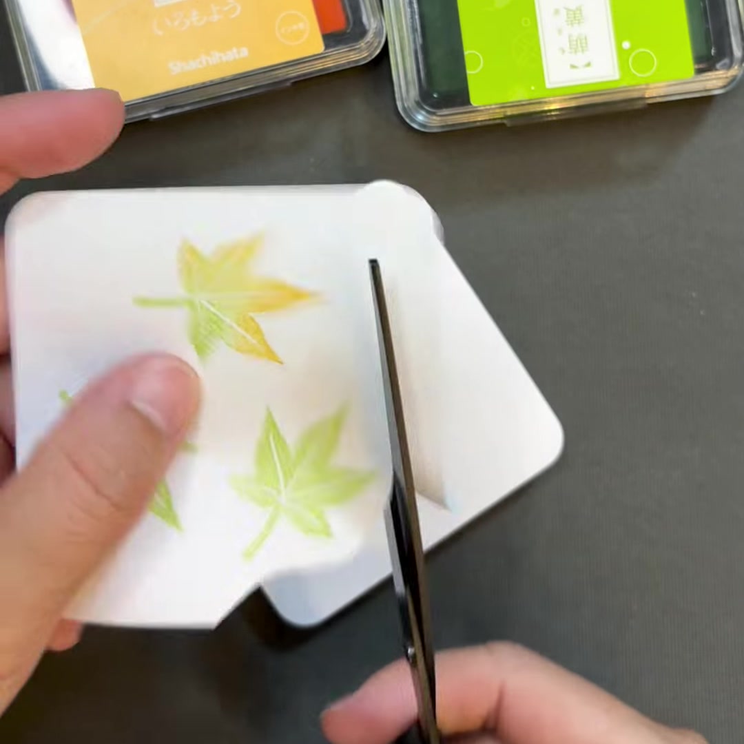 紅葉のはんこを捺したふせんをはさみで切り抜く